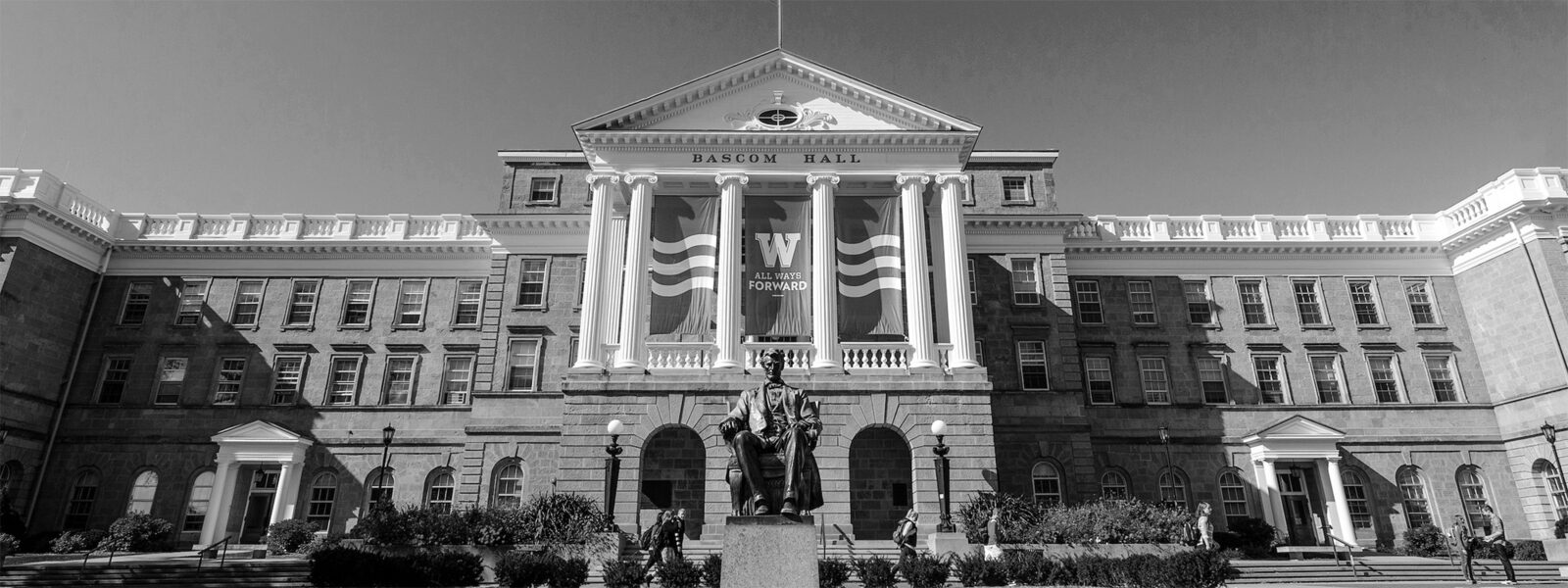 Greyscale image of Bascom Hall with banners featuring the iconic W and the phrase 'All Ways Forward'.